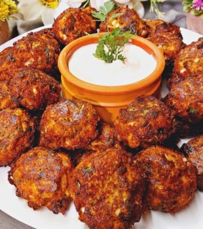 Greek Eggplant Fritters in a plate with sauce - Melitzanokeftedes